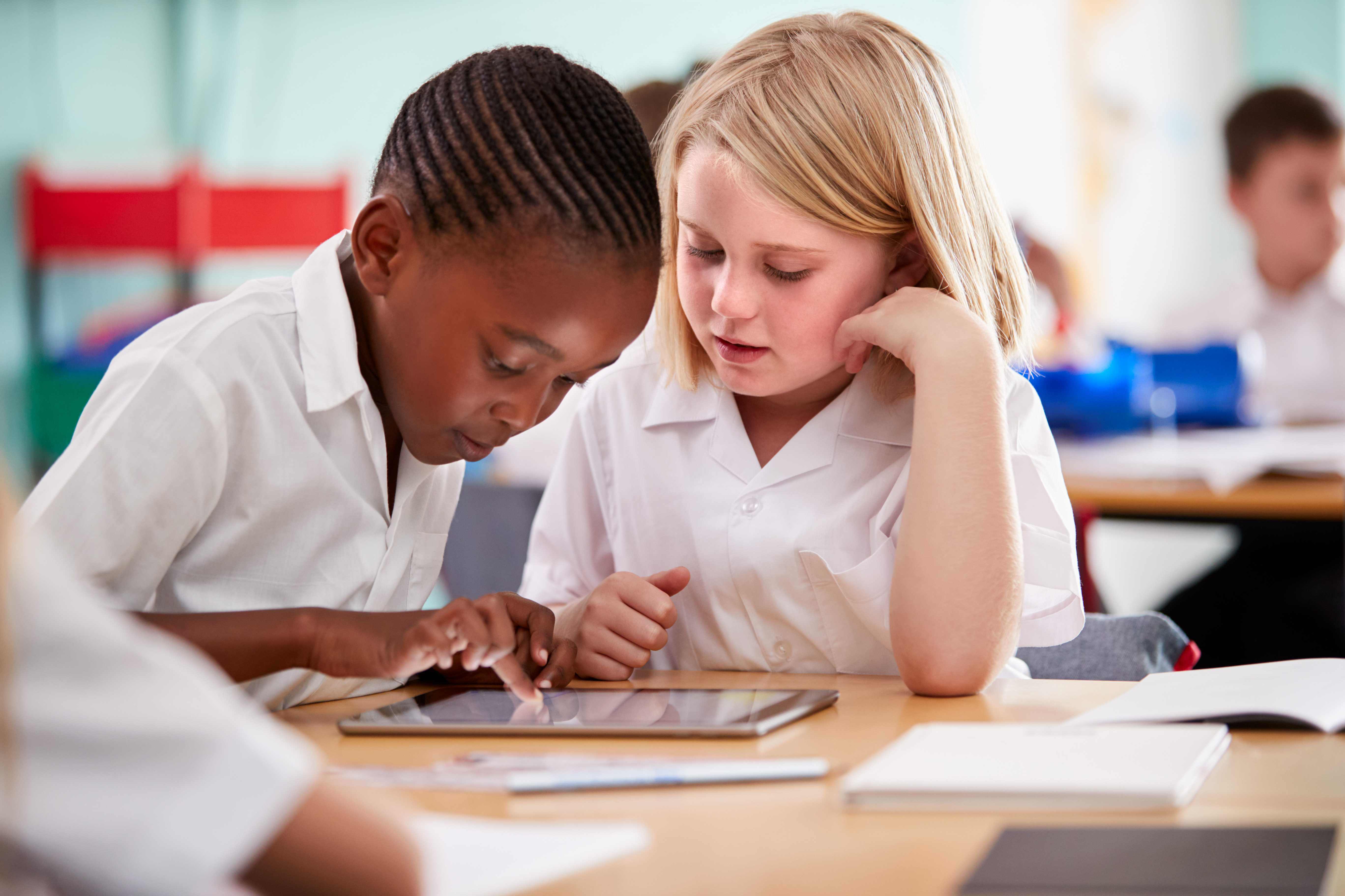 Children studying in school with new tablet amid NCETM discussions